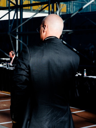 A bald man in a suit with his back turned looking into the distance at Hillary Clinton's election ni...