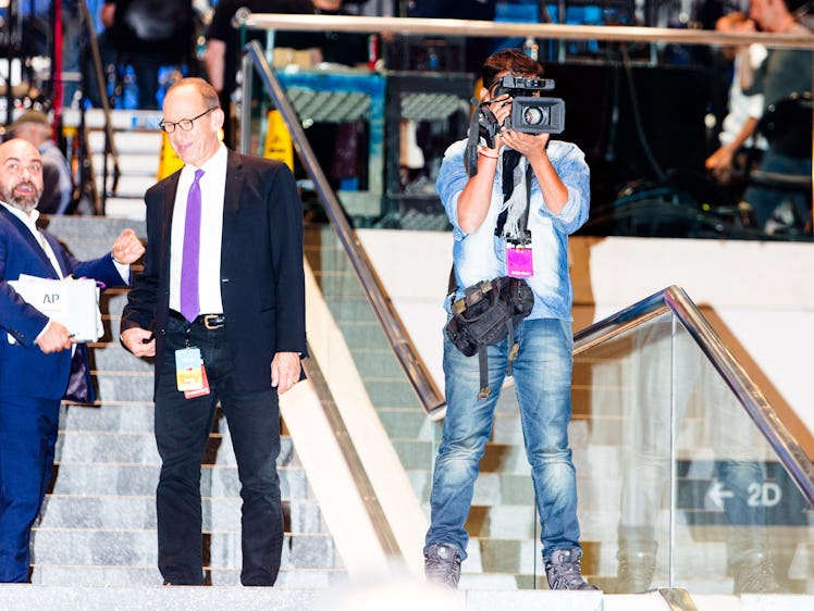 A cameraman standing and filming on the stairs of the Jacob K. Javits Convention Center