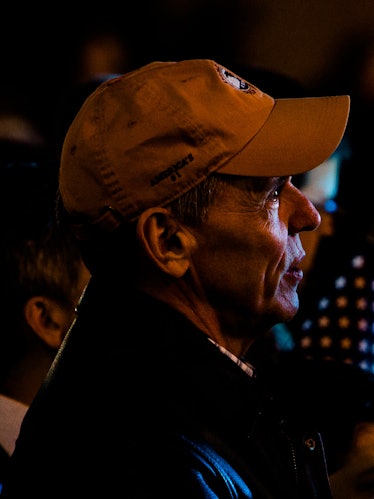 A closeup of a man in a yellow cap looking towards the stage at Hillary Clinton's election night ral...