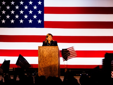 A woman speaking at the stand during Hillary Clinton's election night party, with the U.S. flag behi...