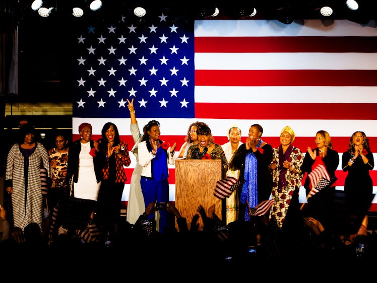 A group of women speaking at Hillary Clinton's election night rally with the U.S. flag behind them