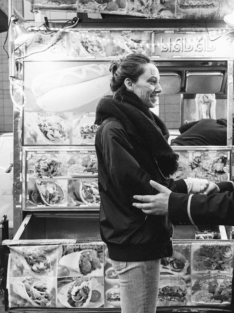 A man and a woman smiling and shaking hands in front of a fast food truck 