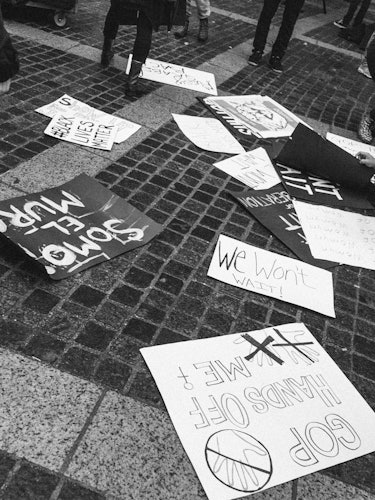 A bunch of various protest signs laid out on the street next to each other with different texts