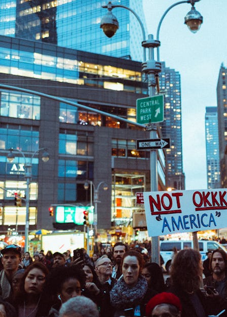 A crowd of demonstrators during a protest having occupied an entire street and a poster 'NOT OKKK 'A...