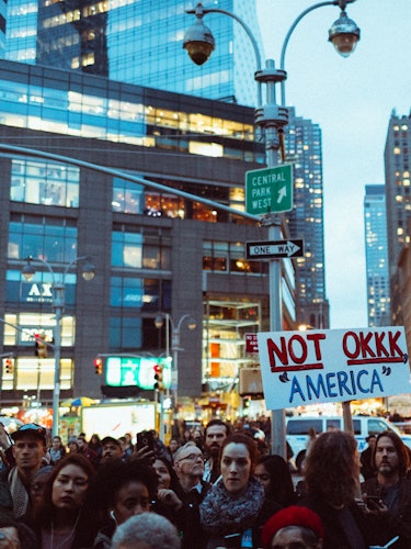 A crowd of demonstrators during a protest having occupied an entire street and a poster 'NOT OKKK 'A...