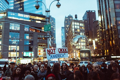 A crowd of demonstrators during a protest having occupied an entire street and a poster 'NOT OKKK 'A...
