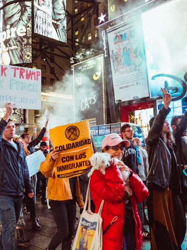 A group of activists during a protest holding protest signs against Donald Trump