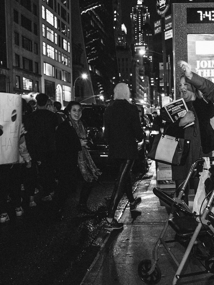A group of activist crossing the street with protest signs against Donald Trump