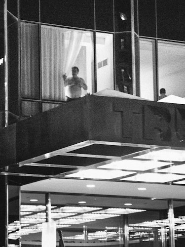 A man in underwear looking through the window of a building