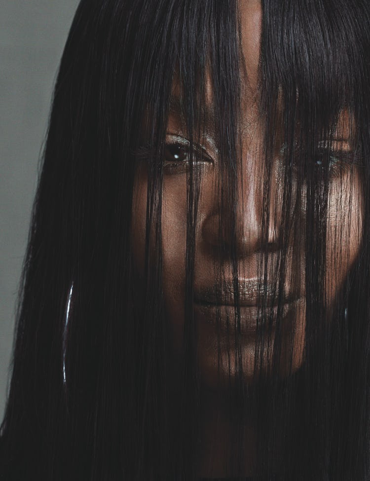 A portrait of Naomi Campbell with her face covered with her hair