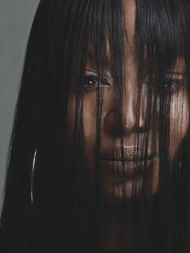 A portrait of Naomi Campbell with her face covered with her hair