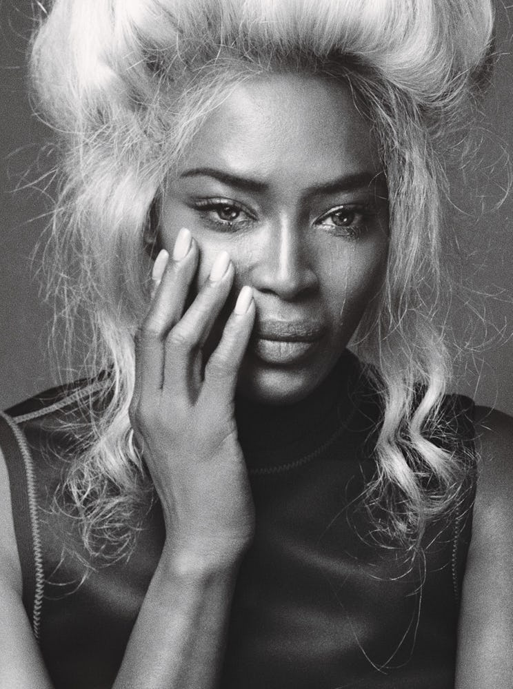 A portrait of Naomi Campbell in a black dress and a blonde wig