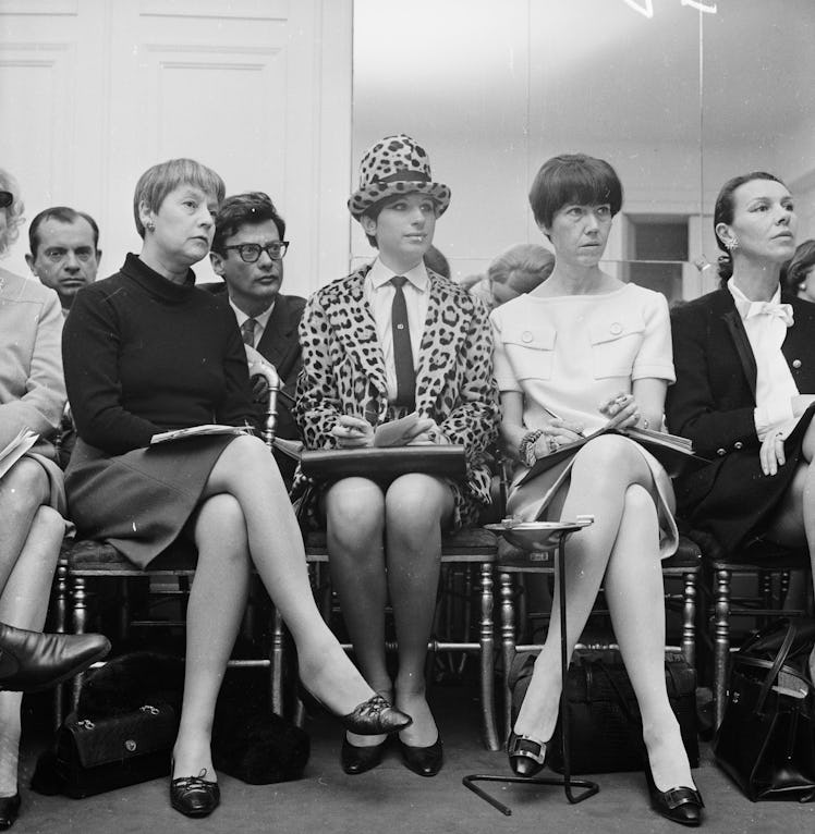 Barbra Streisand sitting front row at Chanel in 1966 wearing a leopard print blazer and hat, a white...