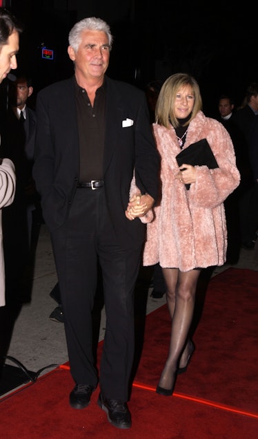 James Brolin in a black suit and shirt and Barbra Streisand in a short pink coat at a red carpet eve...