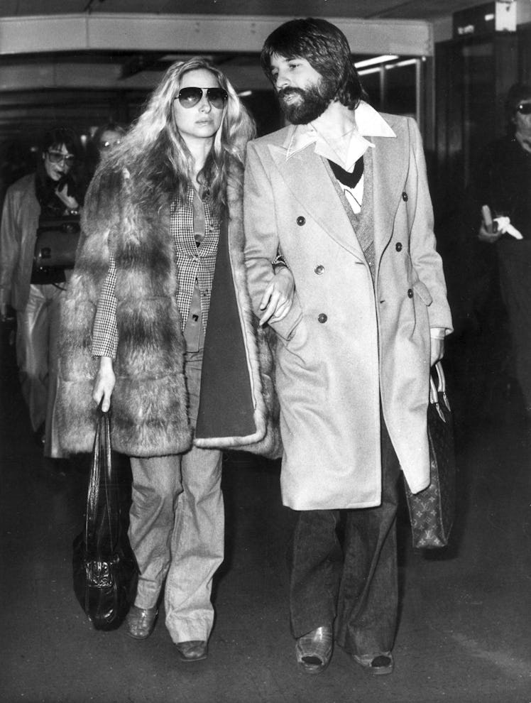 Barbra Streisand in a suit and fur coat and Jon Peters in a coat and trousers in 1975