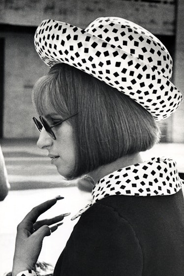 Barbra dressed in a black coat, with a polka dot collar, topped with a matching polka dot hat on her...