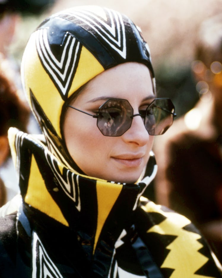 Streisand wearing sunglasses and a futuristic black, yellow, and white outfit