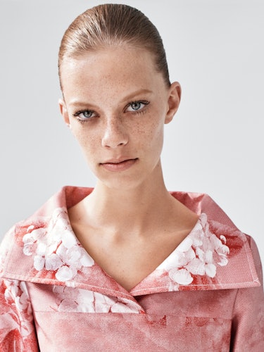 A portrait of a model in a pink floral jacket