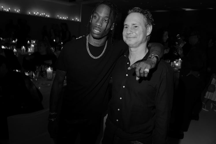 Travis Scott standing with his arm around the neck of a man who is smiling