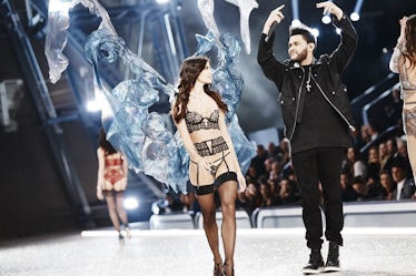 A model walking in black lace lingerie and blue tulle wings next to The Weeknd at the 2016 Victoria’...