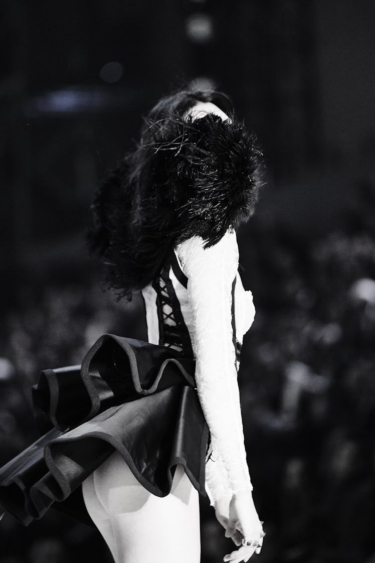 A side-view of a model in a black-white outfit with feather elements at the 2016 Victoria’s Secret F...