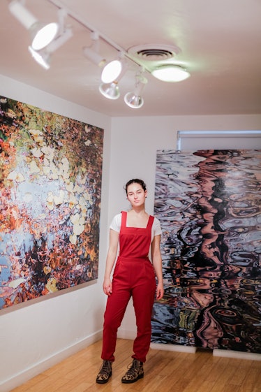 A woman in a red jumpsuit standing in front of a painting at Art Basel Miami Beach 2016.