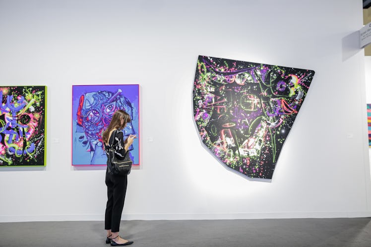 Art enthusiasts observing artworks at Art Basel Miami Beach 2016.