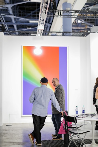 Art enthusiasts discussing artworks at Art Basel Miami Beach 2016.