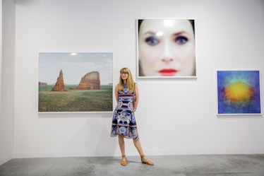 A woman in a patterned dress posing beside the paintings at Art Basel Miami Beach 2016.