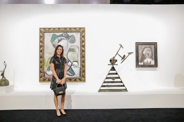 A woman in a black dress posing beside a painting at Art Basel Miami Beach 2016.