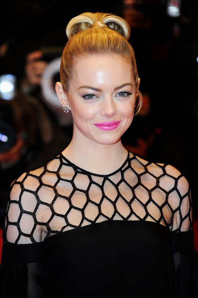 Emma Stone with a top bun and a pink lip, wearing a black dress at The Croods film premiere in 2013