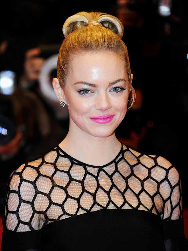 Emma Stone with a top bun and a pink lip, wearing a black dress at The Croods film premiere in 2013