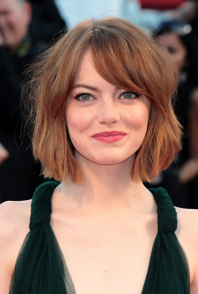 Emma Stone with a tousled bob, wearing a black dress while attending he 71st Venice Film Festival in...