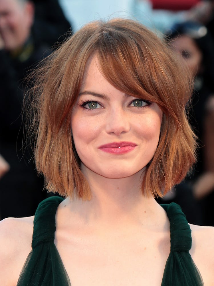 Emma Stone with a tousled bob, wearing a black dress while attending he 71st Venice Film Festival in...