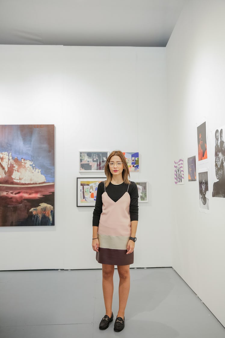A woman wearing a pink camisole dress over a black top paired with black loafers at Art Basel Miami ...