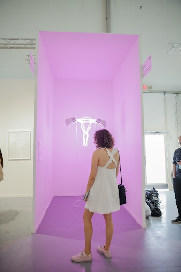 A woman in a white dress looking at the art installation at Art Basel Miami Beach 2016.