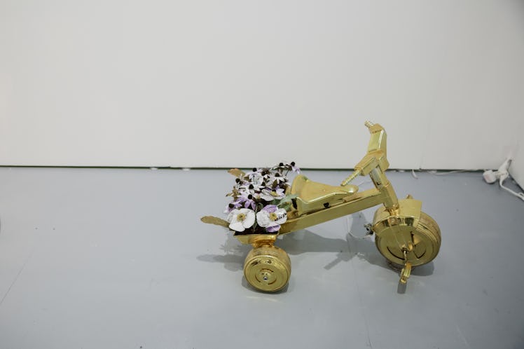 A sculpture of a golden tricycle with flowers in it at the 2016 Art Basel Miami Beach.