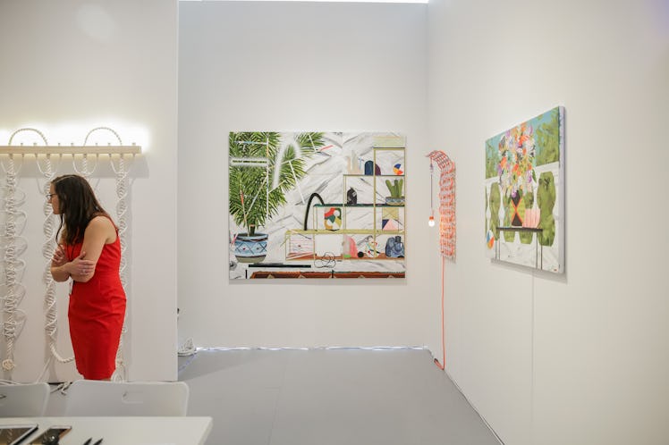 A woman in a red dress observing artwork at the 2016 Art Basel Miami Beach.