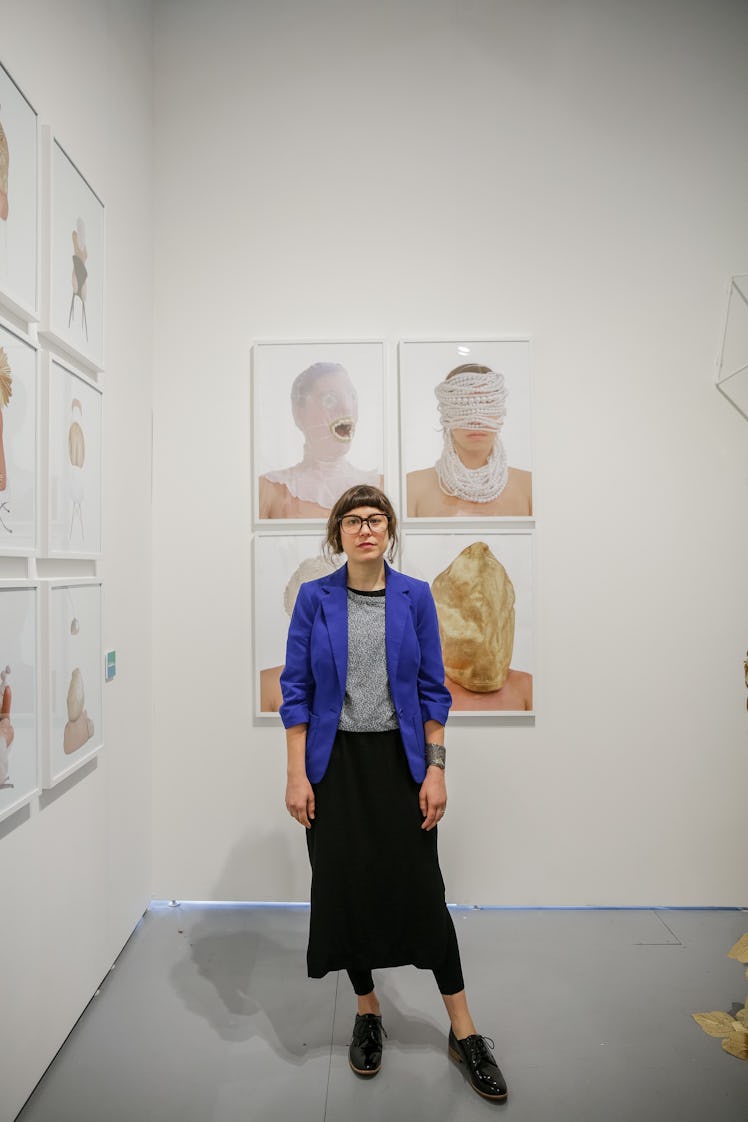 A woman posing in front of paintings at the 2016 Art Basel Miami Beach showcase.