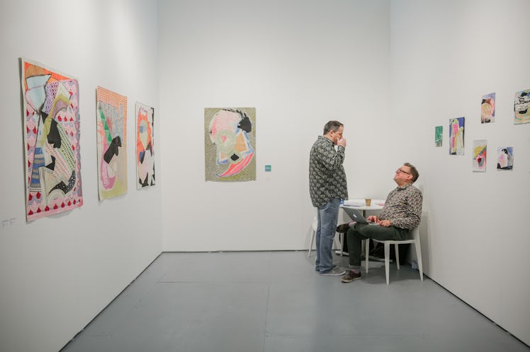 Two men talking while looking at the paintings at the 2016 Art Basel Miami Beach showcase.