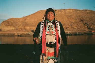 A Native American man standing next to a lake at Standing Rock