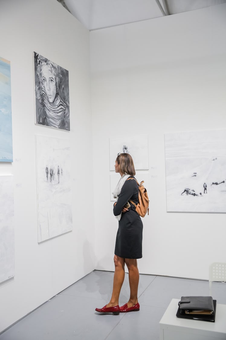 A woman in a black dress admiring art exhibition at Art Basel Miami Beach 2016.