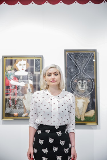 A woman posing in front of the paintings displayed at the 2016 Art Basel Miami Beach.
