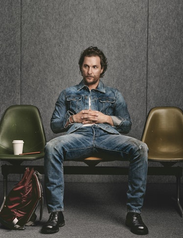 Matthew McConaughey in a blue denim jacket and pants sitting on a chair in a waiting room