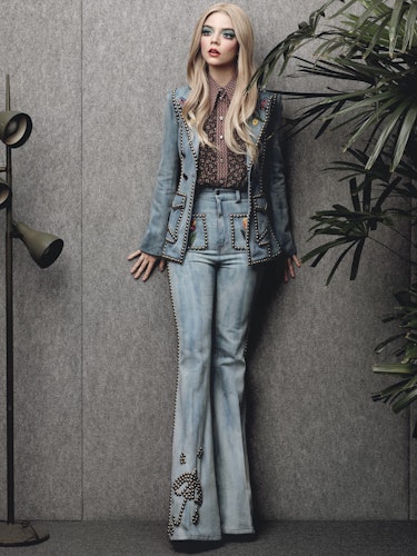 Anya-Taylor Joy standing a posing while wearing a brown floral shirt and a denim suit