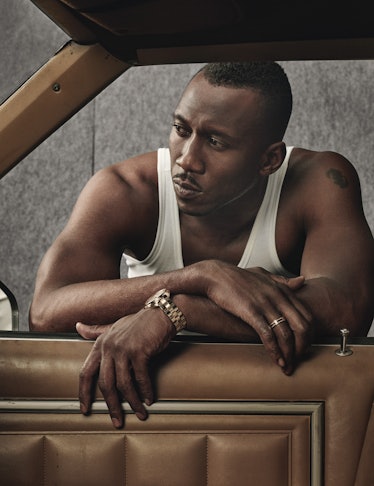 Mahershala Ali in a white top looking into a car
