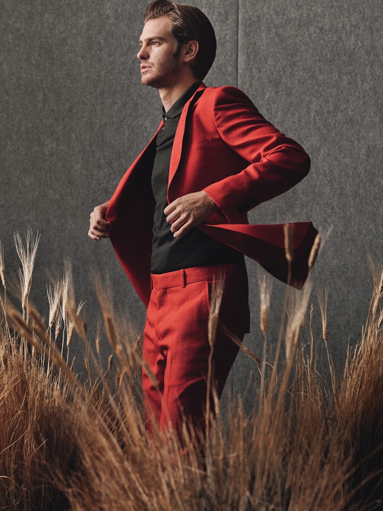 Andrew Garfield standing and posing in a red suit and a black shirt