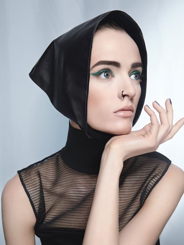 A model with a black headscarf, a mesh black top and blue eyeshadow 