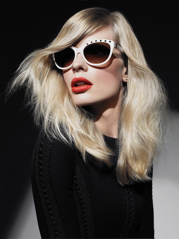 A blonde model in white sunglasses, red lipstick and a black top 