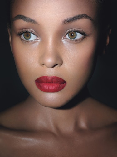 A model with green eyes, light shimmery eyeshadow and red lipstick 